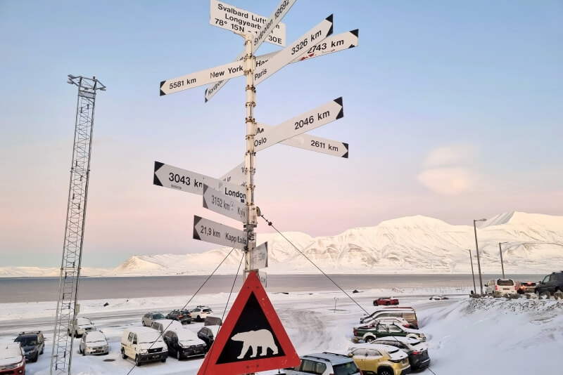 雪山とフィヨルドを背景に、スヴァールバル空港前にある距離標