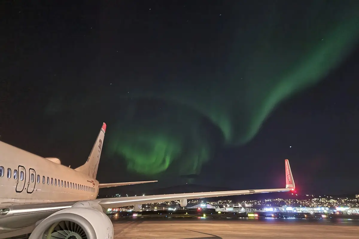 トロムソ空港に駐機する飛行機と夜空に広がるオーロラ