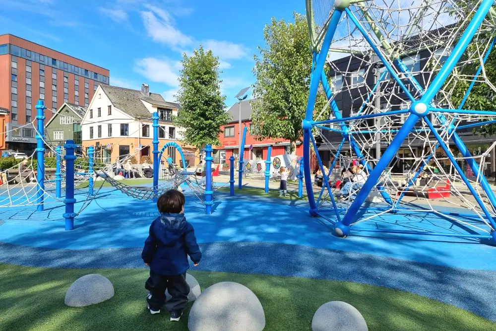 トロムソ中心部の公園で、青いロープ遊具に近づく息子