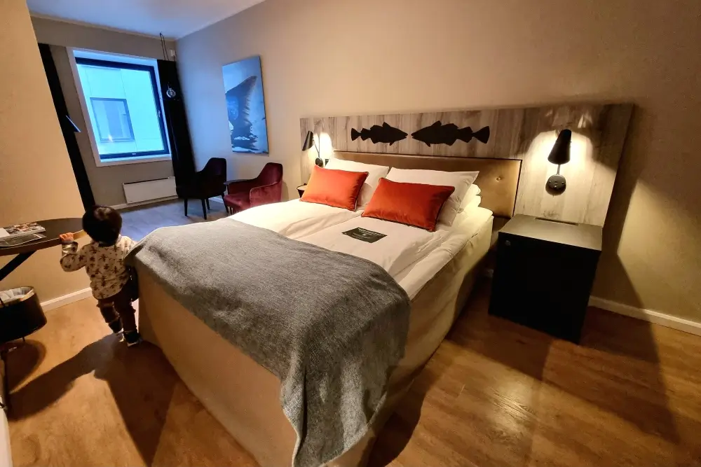 Quality Hotel Grand Tromsøの木目の床と大きなベッドがある客室